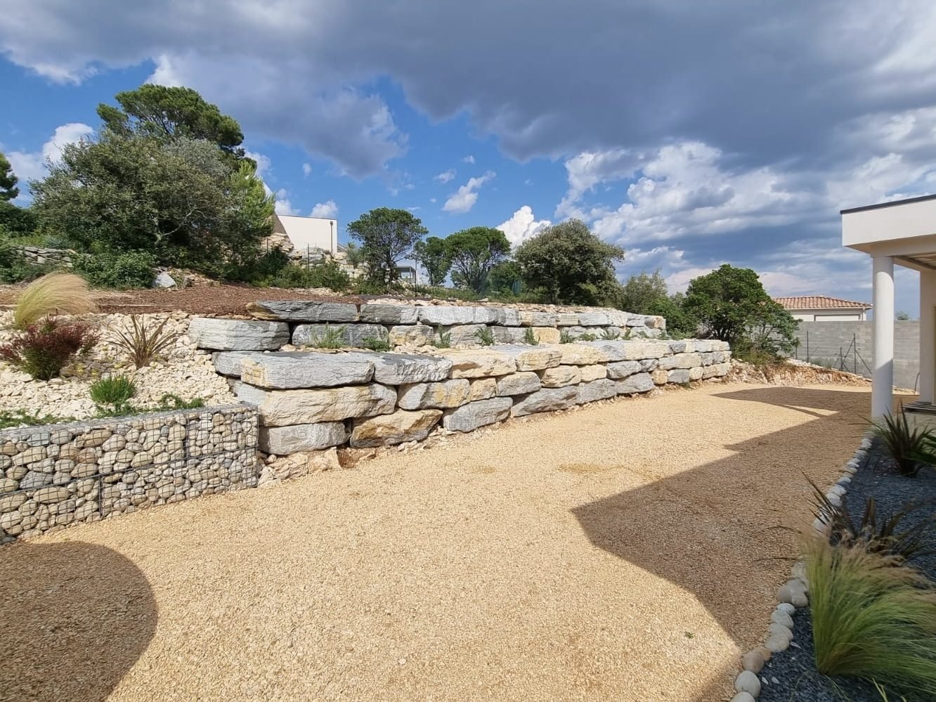 Murs de soutènement en enrochement et gabion, cour en gravier et graminées