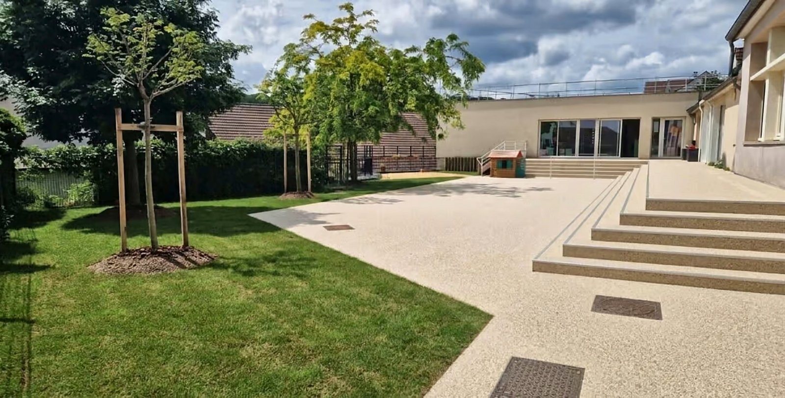 Cour d'école en moquette de pierre drainante, en bordure de pelouse